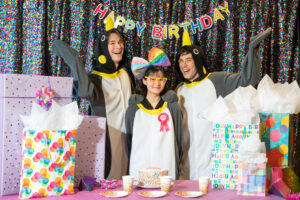 Three people dressed up as penguins at a birthday party