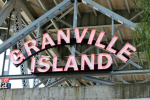 A photograph of the Granville Island neon sign underneath the Granville Street bridge.