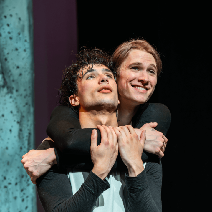 Two actors embracing each other, one performer holding another performer.