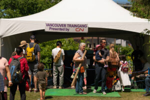 A group of people standing around and underneath the Vancouver Traingang tent.