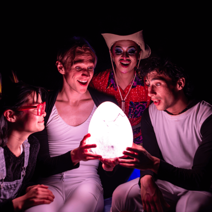 Four people looking at a glowing egg.